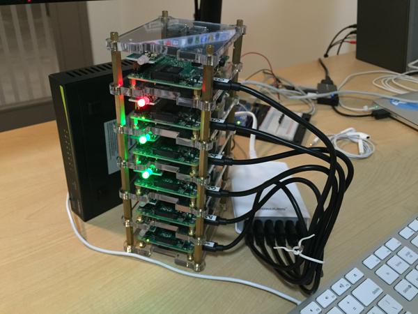 The Dramble: six Raspberry Pi boards stacked in a clear acrylic case on a desk with status LEDs lit